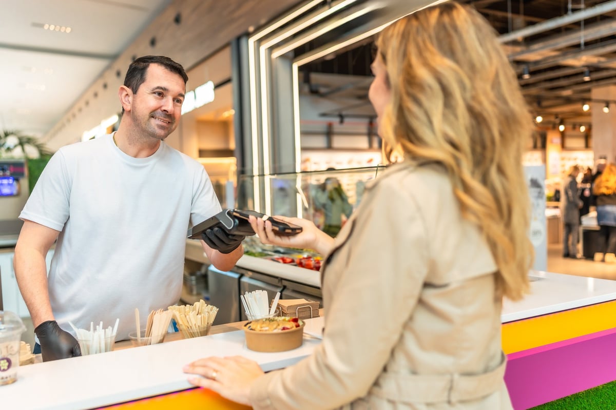 Two people completing a contactless smartphone payment at a terminal
