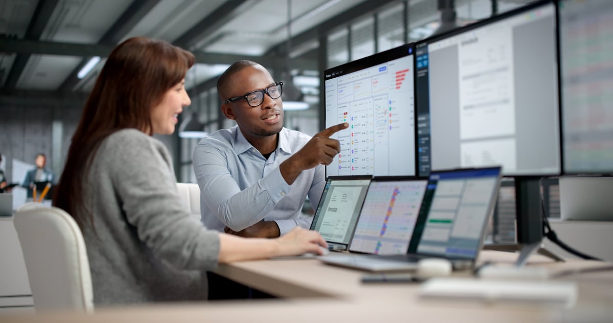 Two professionals analyzing financial reports on computer screens